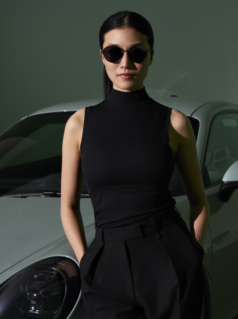Woman with Porsche Design sunglasses in front of a Porsche car.